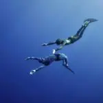 Two freedivers – the man and the woman – are making the simultaneous dive at the depth of Blue Hole, Red Sea, Egypt. The picture seems very romantic.