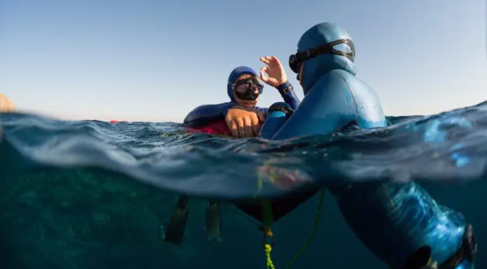 Split shot of two free divers training in sea with buoy