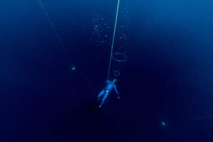 Free diver making air bubbles ring deep underwater