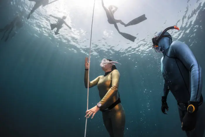 Freediver practicing pulling on the rope with her instructor watching.