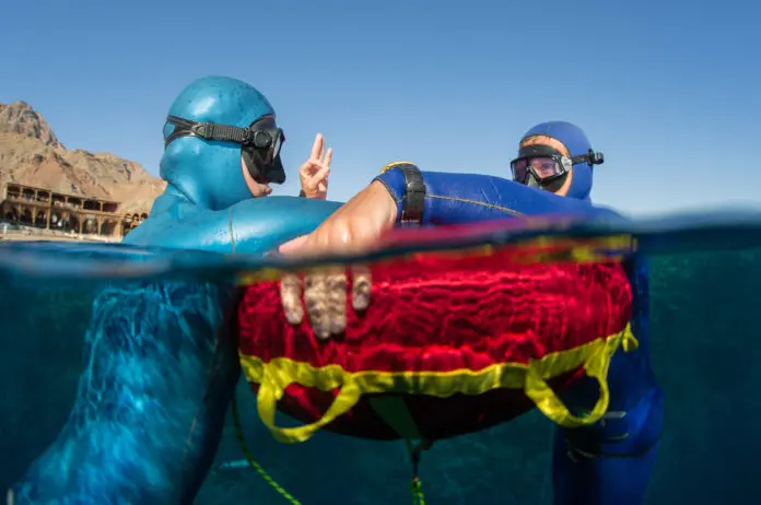 Two freedivers training in sea with buoy