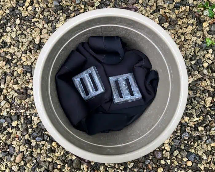 Put your neoprene wetsuit into a bucket and weigh it down.