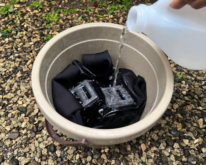 Pour the isopropyl alcohol into the bucket to fully cover the wetsuit.
